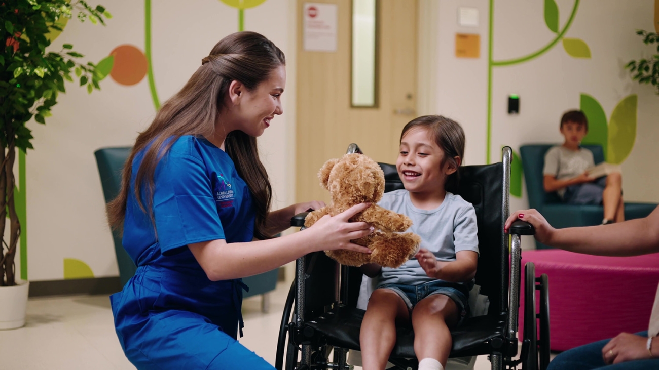 nurse handing girl a teddy bear